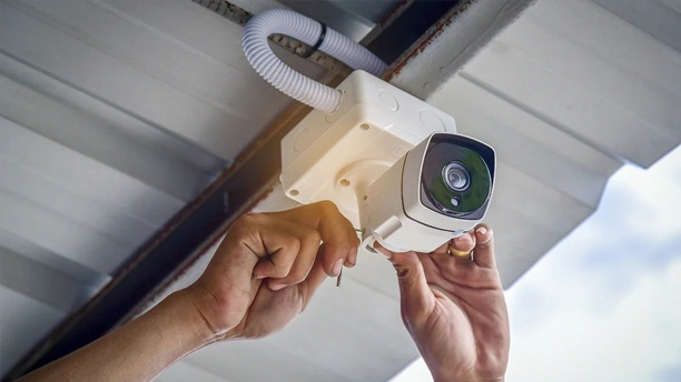 Professional technician installing a smart surveillance camera system for property security in Riverside, CA.